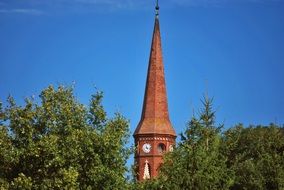 brick tower of church behind trees