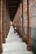 person walking on long passage of brick building, gtrmany, berlin,