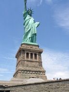 Statue of Liberty at the background of the sky with white clouds