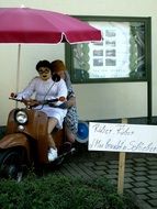 people are sitting on a scooter near the house