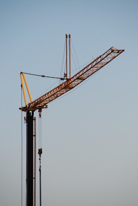 yellow crane with boom on gray sky background