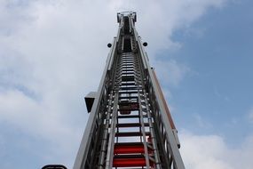 fire truck ladder upward view at white cloudy blue sky