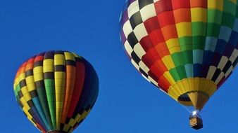 two bright hot air balloons in the blue sky