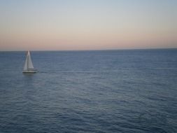 distant view of sailboats in the ocean at dusk