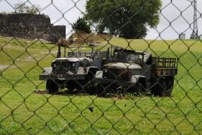 two old military trucks on the fence