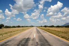free bitumen road through meadow to distant mountains