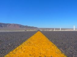 yellow dividing strip on asphalt road close up