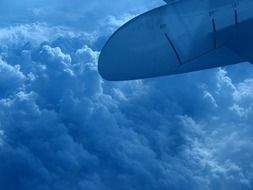 plane wing over thick white clouds close up