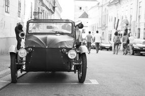 black and white picture of on an old car on the street