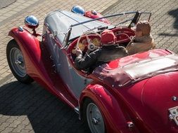 people in red vintage open-top car