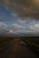 dark road into the distance under storm clouds