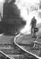 man at steam locomotive on railway