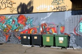 trash containers at wall with graffiti