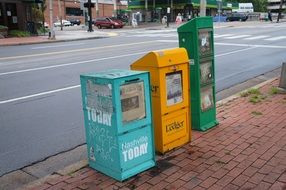 three newspaper boxes on a city street