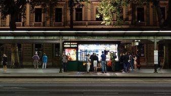 people at the bus stop in the evening