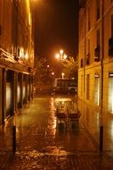 pile of chairs on street on rainy night