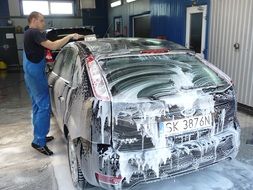 The man washes the car with foam