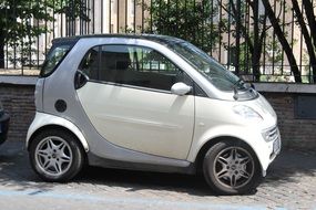 White smart car parked near an iron fence