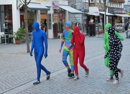 several people walk down the street in colorful costumes