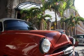 front of red oldtimer car, cuba