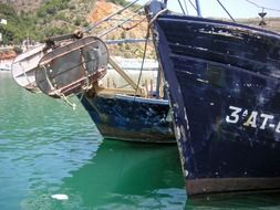 fronts of two weathered fishing boats on water