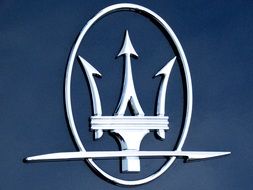 silver logo of maserati car brand at deep blue surface
