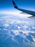 wing of an airplane over a snowy landscape