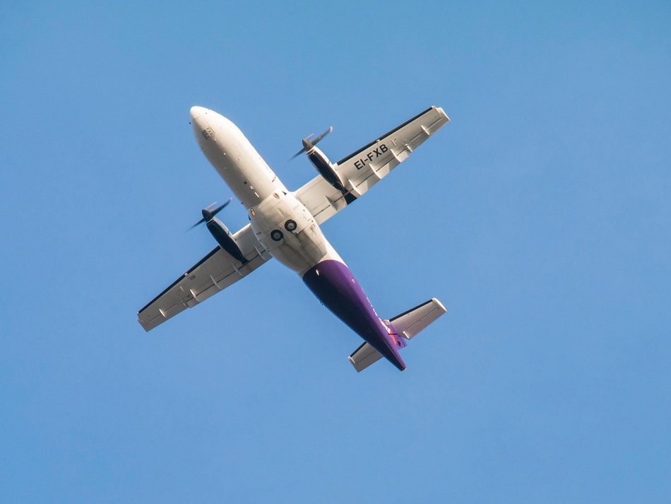 Under view of the colorful flying airplane at blue sky background
