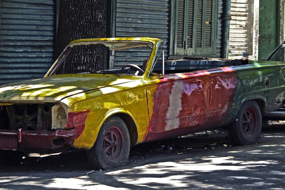 damaged colorful old truck near a shabby building