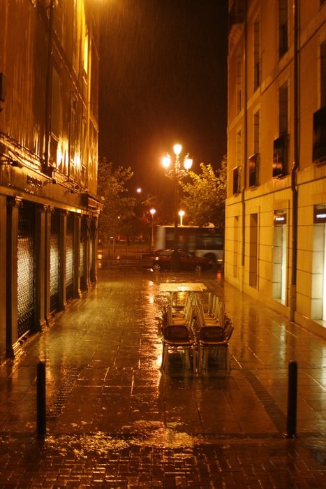 pile of chairs on street on rainy night