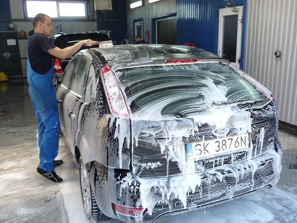 The man washes the car with foam