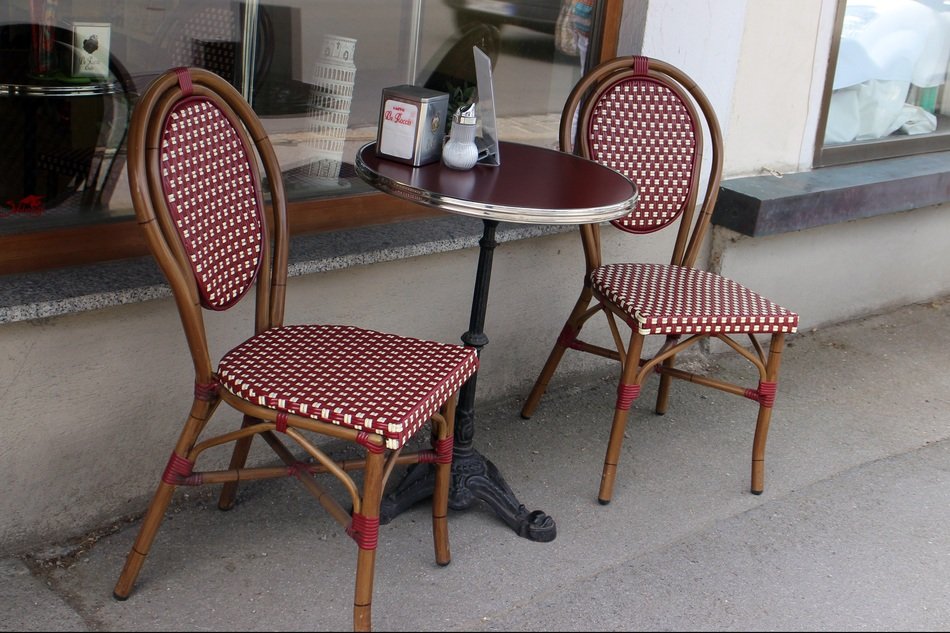 table with red and white chairs on the street near the bistro