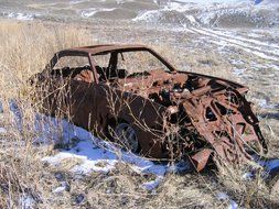 Abandoned rusty car on a pasture.