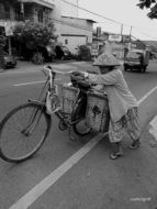 Black and white photo of a woman with a bicycle on the street