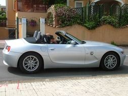 people in silver convertible bmw car at house