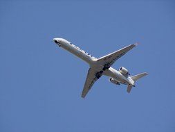 plane flies under the blue sky