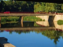 automobile bridge is reflected in the river among picturesque nature