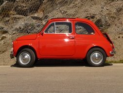 red car stands near a stone wall