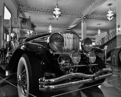 black and white photo of an antique car in a museum