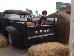 Kid on the vehicle ford near the dry grass