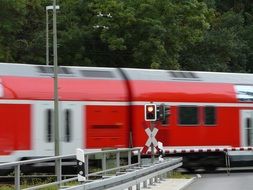 red train through the railway crossing