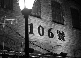 street lantern at wall with number 106, black and white