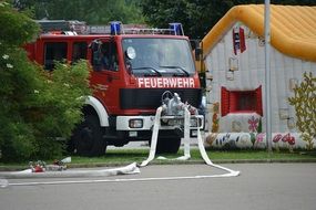 fire truck with attached water hoses in front of building