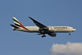 emirates plane with passengers flying in the sky with clouds