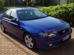 blue car stands on a cobblestone road