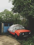 vintage audi, red car parked in front of garage