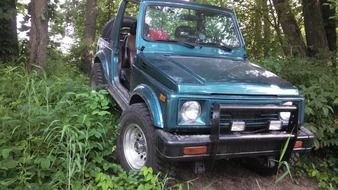 jeep drives off a hill in the forest
