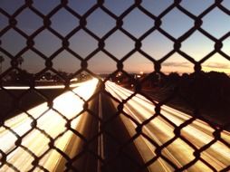 night photo of city traffic through a metal mesh