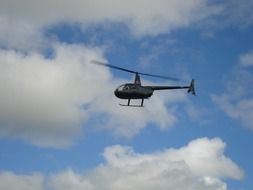 hovering helicopter in sky beneath clouds