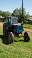 old tractor stands on green grass in summer